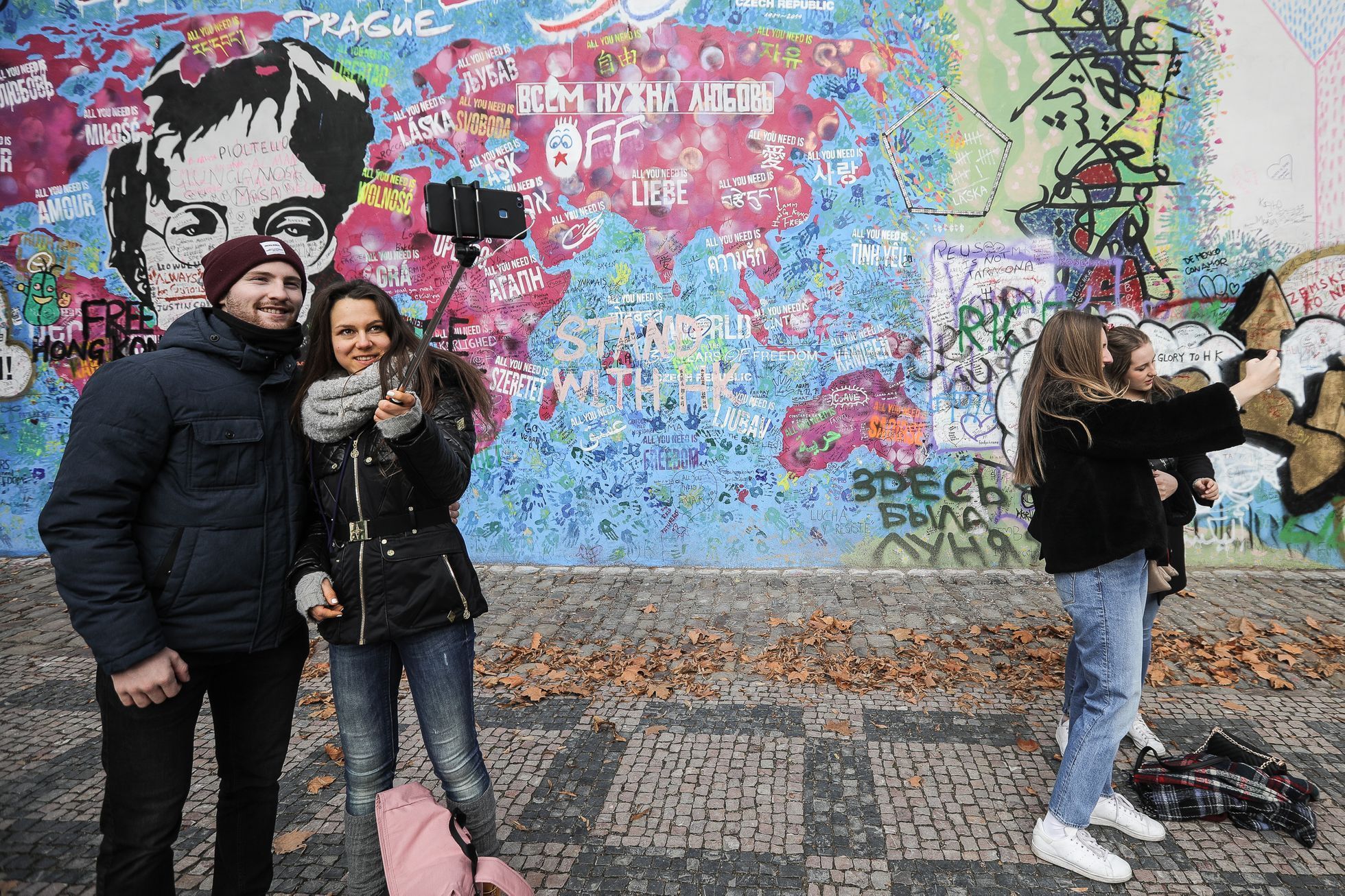 Lennonova zeď po třech měsících od malování - turisté, graffiti