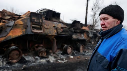 Civilista vedle zničené ruské obrněné techniky ve městě Buča v Kyjevské oblasti na Ukrajině. 1. 3. 2022