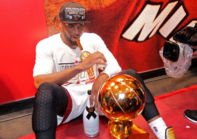 Miami Heat's Dwyane Wade sits with the Larry O'Brien Trophy after his team defeated the San Antonio Spurs in Game 7 to win their NBA Finals basketball playoff in Miami, F