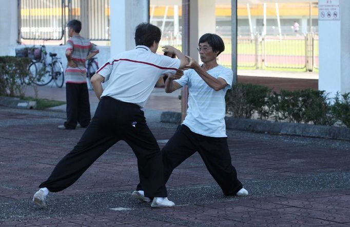 Vedle velké skupiny cvičící Tai-chi se tito dva muži věnovali jinému bojovému umění. Za nimi je vidět stadion, kde od brzkých ranních hodin kroužili na oválu běžci, a ve stínu se skupinka věnovala cvičení jógy. Na druhé straně se zase hrál tenis. Otevřený byl také nedaleký bazén, kde byli první plavci.