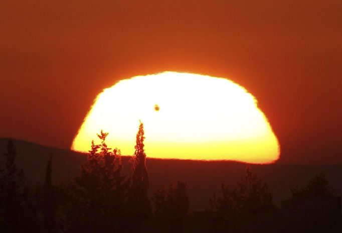 The planet Venus is seen as a black dot as it makes its transit across the sun over Amman June 6, 2012. Venus made a slow transit across the face of the sun on Tuesday, the last such passing that will be visible from Earth for 105 years. REUTERS/Ali Jarekji (JORDAN - Tags: ENVIRONMENT SCIENCE TECHNOLOGY) Published: Čer. 6, 2012, 5:45 dop.