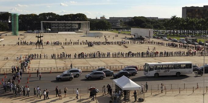 People line up in front of Planalto Palace to attend the funeral of Oscar Niemeyer in Brasilia December 6, 2012. Niemeyer, a towering patriarch of modern architecture who shaped the look of modern Brazil and whose inventive, curved designs left their mark on cities worldwide, died late on Wednesday. He was 104. Niemeyer had been battling kidney and stomach ailments in a Rio de Janeiro hospital since early November. His death was the result of a lung infection developed this week, the hospital said, little more than a week before he would have turned . REUTERS/Paulo Whitaker (BRAZIL - Tags: SOCIETY OBITUARY) Published: Pro. 6, 2012, 8:28 odp.