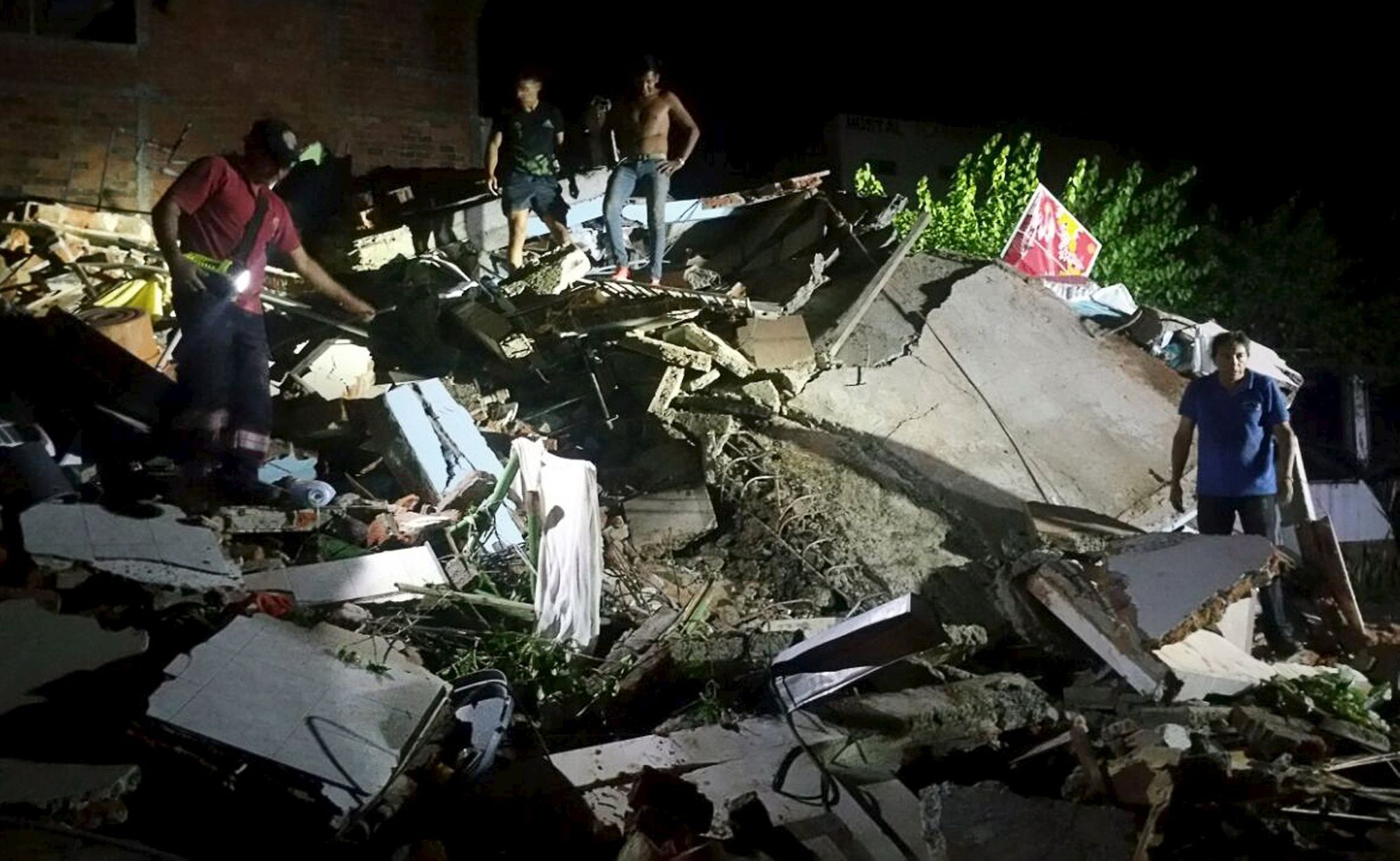 People stand next to the debris of a building after a 7.8 magnitude earthquake struck off the country's northwest Pacific coast causing &quot;considerable damage&quot;, in Manta