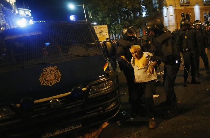 Riot police hold up a demonstrator who was hit on the head outside the Spanish parliament in Madrid, September 25, 2012. Protesters clashed with police in Spain's capital on Tuesday as the government prepares a new round of unpopular austerity measures for the 2013 budget that will be announced on Thursday. REUTERS/Susana Vera (SPAIN - Tags: CIVIL UNREST POLITICS BUSINESS) Published: Zář. 25, 2012, 8:41 odp.