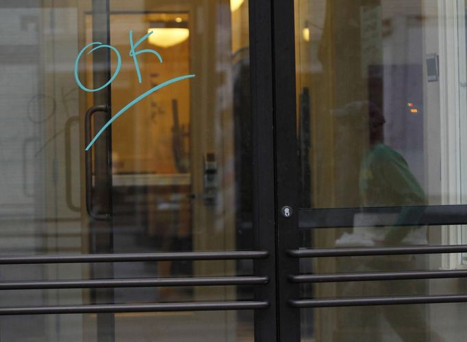 A person is reflected in a glass door with the word "OK" scrawled on it on Boylston Street after the street reopened to the public for the first time since the Boston Marathon bombings in Boston, Massachusetts April 24, 2013. REUTERS/Jessica Rinaldi (UNITED STATES - Tags: CRIME LAW CIVIL UNREST) Published: Dub. 24, 2013, 12:37 odp.