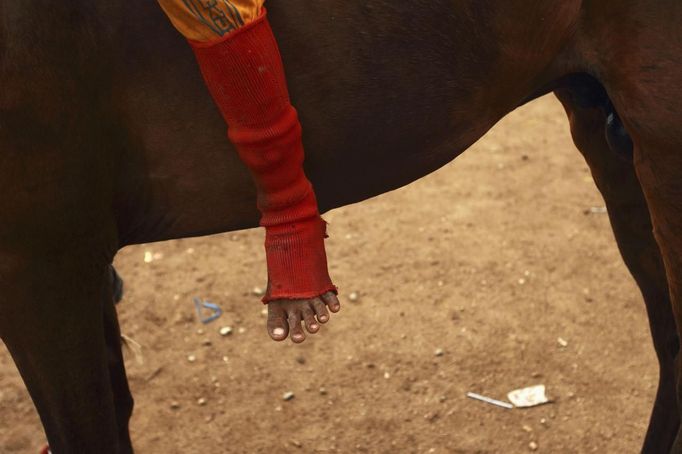 The foot of child jockey is seen as he sits on his horse at Panda racetrack outside Bima, November 18, 2012. Dozens of child jockeys, some as young as eight-years-old take part in the races. Involving nearly 600 horses they take place around a dusty, oval track of 1,400 meters (nearly one mile). The reward, for the winner is a handful of cash for his family, and glory for the jockey. The grand prize is one million rupiah ($100). Those who win their groups get two cows. The chairman of the races' organising team, Hajji Sukri, denies that there is any danger to the children saying they are all skilful riders and none has been killed or seriously hurt. Picture taken November 18, 2012. REUTERS/Beawiharta (INDONESIA - Tags: SPORT SOCIETY) ATTENTION EDITORS: PICTURE 19 of 25 FOR PACKAGE 'BETTING ON CHILD JOCKEYS' Published: Lis. 24, 2012, 9:16 dop.