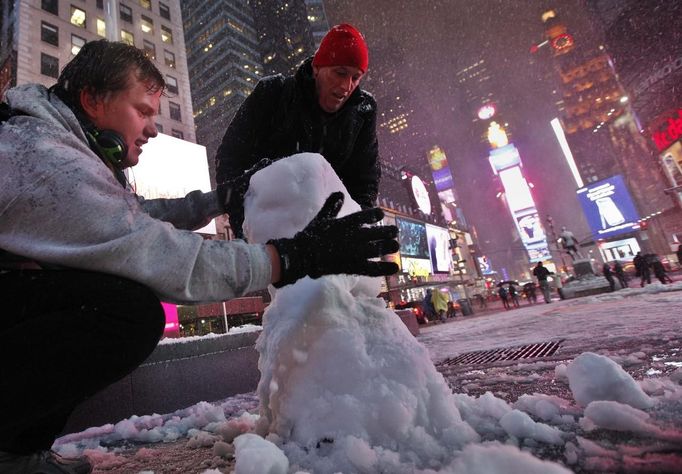 Henrik (L) a tourist visiting from Norway and John from Wayne, New Jersey build a snowman together during a snow storm in New York's Times Square, November 7, 2012. A wintry storm dropped snow on the Northeast and threatened to bring dangerous winds and flooding to a region still climbing out from the devastation of superstorm Sandy. REUTERS/Brendan McDermid (UNITED STATES - Tags: DISASTER ENVIRONMENT) Published: Lis. 8, 2012, 2:48 dop.