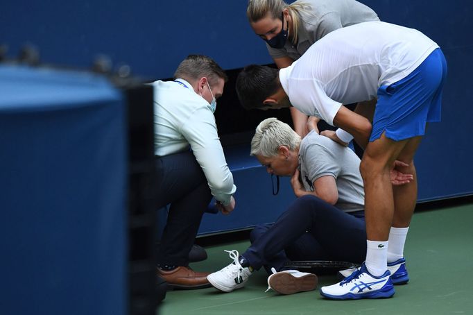 Sep 6, 2020; Flushing Meadows, New York, USA; Novak Djokovic of Serbia and a tournament official tend to a linesperson who was struck with a ball by Djokovic against Pabl