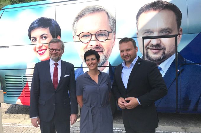 Předsedové stran koalice Spolu před volebním autobusem, na kterém jsou jejich portréty.