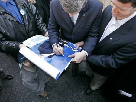 Konzervativec Stephen Harper podepisuje volební plakáty