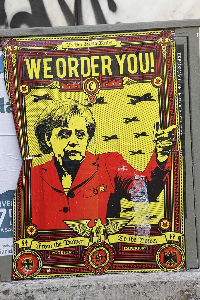 Anti-German political protest poster in Lisbon, Portugal - 11 Dec 2011 2011-12-11 00:00:00 Mandatory Credit: Photo by Stuart Forster / Rex Features (1521406a) Poster of German Chancellor Angela Merkel and a squadron of military bomber aircraft which reads 'We Order You!', Lisbon, Portugal Anti-German political protest poster in Lisbon, Portugal - 11 Dec 2011 A protest poster indicates at political and economic tensions being felt in Europe in late 2011. The poster bears a likeness of German Chancellor Angela Merkel (or Merdel - merda is Portuguese for shit), and a squadron of military bomber aircraft. It is designed in the style of Nazi propaganda from the 1930s and 1940s, complete with iron cross, swastika and gothic typeface.