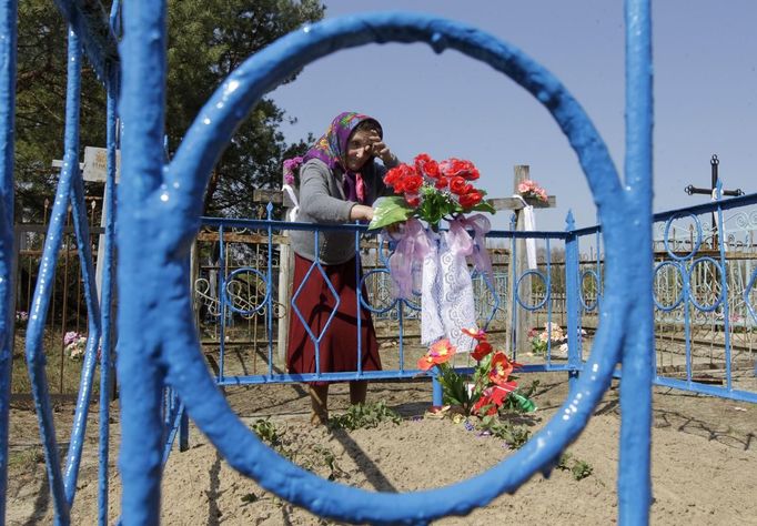 Belarussian woman stands at her relative's grave on the eve of Radunitsa in the abandoned village of Tulgovichi