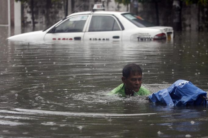 A road emergency crew member unclogs a drain on a flooded street after a heavy downpour in Quezon City, Metro Manila July 3, 2012. Heavy rain has flooded some roads, causing classes to be suspended in parts of Metro Manila, local media reported. REUTERS/Cheryl Ravelo (PHILIPPINES - Tags: ENVIRONMENT) Published: Čec. 3, 2012, 2:07 dop.