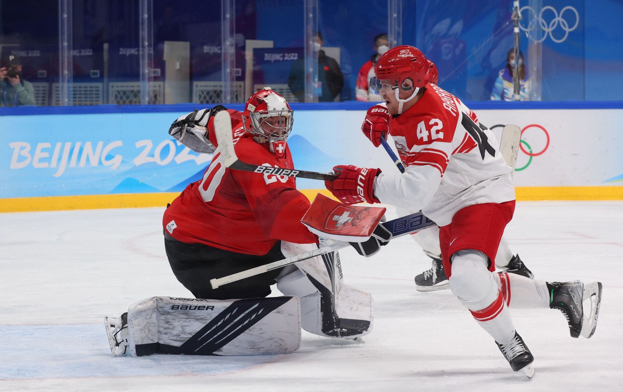 Mikkel Aagaard a švýcarský brankář Reto Berra v zápase Švýcarsko - Dánsko na ZOH 2022 v Pekingu