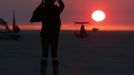 Libriel Padilla watches the sunrise as it is obscured by smoke from the western wildfire during the Burning Man 2012 "Fertility 2.0" arts and music festival in the Black Rock Desert of Nevada, August 29, 2012. More than 60,000 people from all over the world have gathered at the sold out festival, which is celebrating its 26th year, to spend a week in the remote desert cut off from much of the outside world to experience art, music and the unique community that develops.