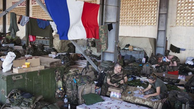 French soldiers talk under a French flag in a hangar at the Malian army air base in Bamako January 14, 2013. France, which has poured hundreds of troops into the capital Bamako in recent days, carried out more air raids on Monday in the vast desert area seized last year by an Islamist alliance grouping al Qaeda's north African wing AQIM alongside Mali's home-grown MUJWA and Ansar Dine militant groups. REUTERS/Joe Penney (MALI - Tags: POLITICS MILITARY CONFLICT) Published: Led. 14, 2013, 6:04 odp.