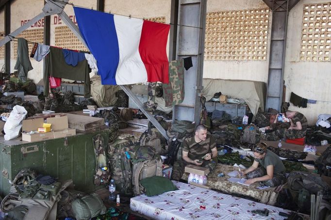 French soldiers talk under a French flag in a hangar at the Malian army air base in Bamako January 14, 2013. France, which has poured hundreds of troops into the capital Bamako in recent days, carried out more air raids on Monday in the vast desert area seized last year by an Islamist alliance grouping al Qaeda's north African wing AQIM alongside Mali's home-grown MUJWA and Ansar Dine militant groups. REUTERS/Joe Penney (MALI - Tags: POLITICS MILITARY CONFLICT) Published: Led. 14, 2013, 6:04 odp.