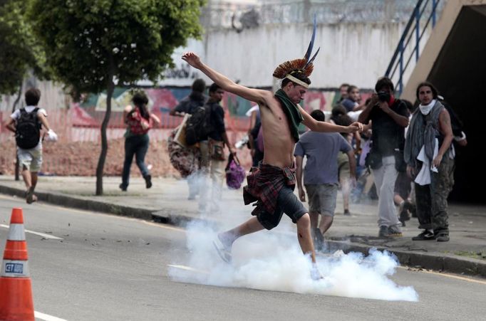 A supporter of the native Indian community kicks a tear gas canister near the Brazilian Indian Museum in Rio de Janeiro March 22, 2013. Brazilian military police took position early morning outside the abandoned Indian museum, where a native Indian community of around 30 individuals have been living since 2006. The Indians were summoned to leave the museum in 72 hours by court officials since last week, local media reported. The group is fighting against the destruction of the museum, which is next to the Maracana Stadium. REUTERS/Sergio Moraes (BRAZIL - Tags: CIVIL UNREST POLITICS) Published: Bře. 22, 2013, 4:19 odp.