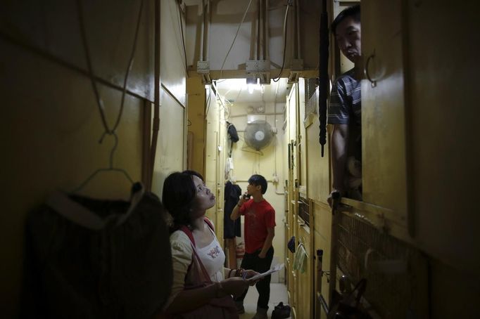 A NGO worker speaks to people living in wooden boxes in Hong Kong early October 9, 2012. In Hong Kong's middle-class residential area, short distance from its shopping and financial districts, 24 people live in these wooden boxes, or "coffin homes", packed in a single apartment of little over 50 square meters. Its residents pay 1450 Hong Kong dollars ($180) for their living space built of wooden panels of 2 meters by 70 cm. To maximize income from the rent in central Hong Kong landlords build "coffin homes", nicknamed due to their resemblance to real coffins. Space has always been at a premium in Hong Kong where developers plant high-rises on every available inch. REUTERS/Damir Sagolj (CHINA - Tags: SOCIETY POVERTY) Published: Říj. 9, 2012, 1:31 odp.