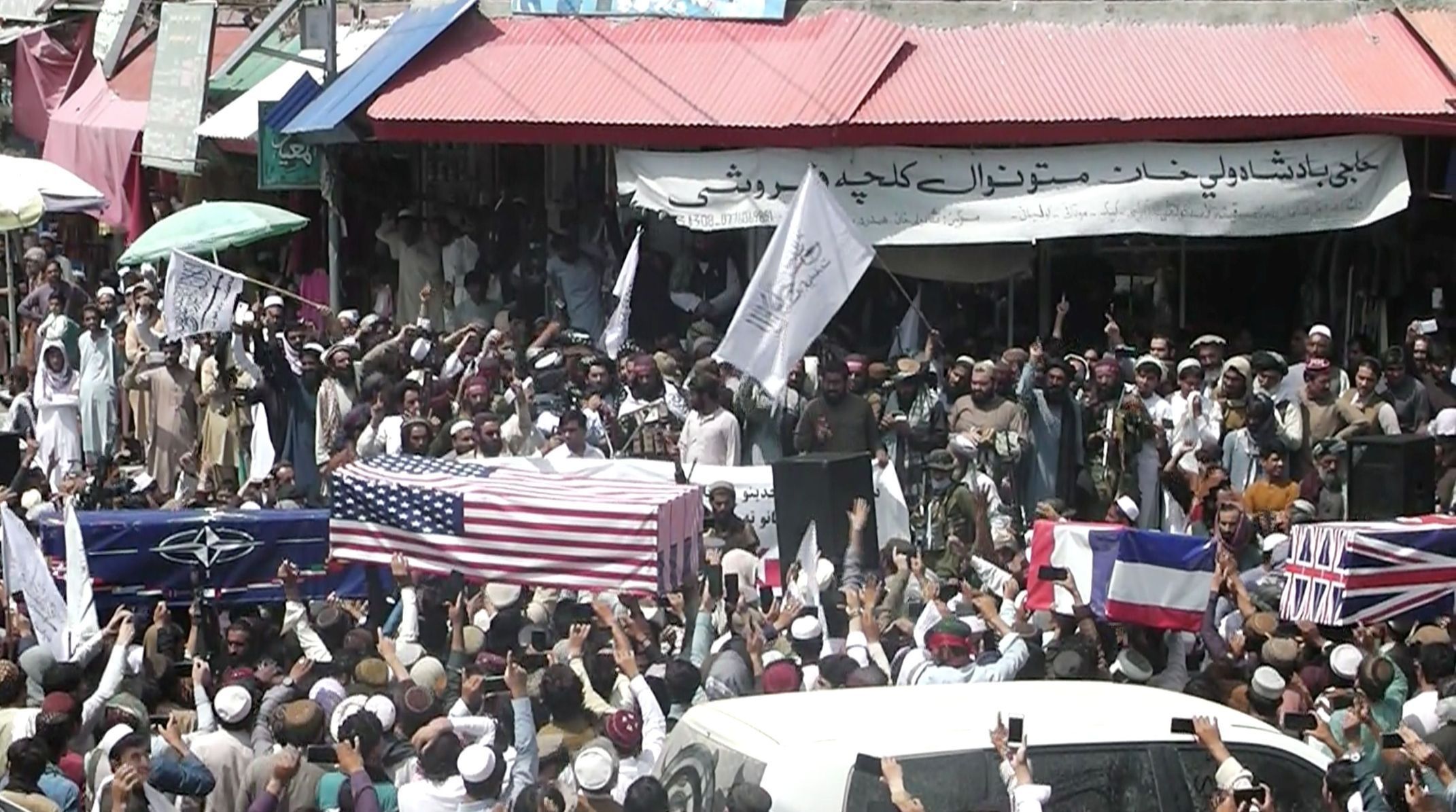 Dav Talibánců nese provizorní rakve přikryté vlajkami NATO a Spojených států během předstíraného pohřbu na ulici v Afghánistánu.