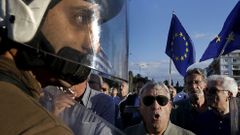 Policista mezi demonstranty v Aténách. Do ulic vyšli v pondělí zastánci i odpůrci eurozóny.