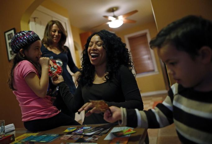 Mercedes Santos (2nd R) shares a laugh with her partner Theresa Volpe (2nd L) while playing cards with their son Jaidon (R) and daughter Ava at their home in Chicago, Illinois, December 22, 2012. Santos and Volpe are a same-sex couple raising two of their biological children as they struggle to get same-sex marriages passed into law in Illinois. Picture taken December 22, 2012. REUTERS/Jim Young (UNITED STATES - Tags: SOCIETY) Published: Bře. 25, 2013, 6:06 odp.