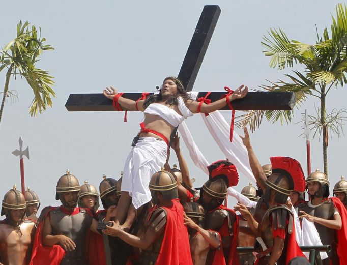 Ruben Enaje, 52, who is portraying Jesus Christ for the 27th time, is raised on a wooden cross by a group of men playing Roman soldiers after he was nailed to it during a Good Friday crucifixion re-enactment in San Pedro Cutud town, Pampanga province, north of Manila March 29, 2013. The Roman Catholic church frowns upon the gory spectacle held in the Philippine village of Cutud every Good Friday but does nothing to deter the faithful from emulating the suffering of Christ and taking a painful route to penitence. Holy Week is celebrated in many Christian traditions during the week before Easter. REUTERS/Romeo Ranoco (PHILIPPINES - Tags: RELIGION SOCIETY) Published: Bře. 29, 2013, 7:24 dop.