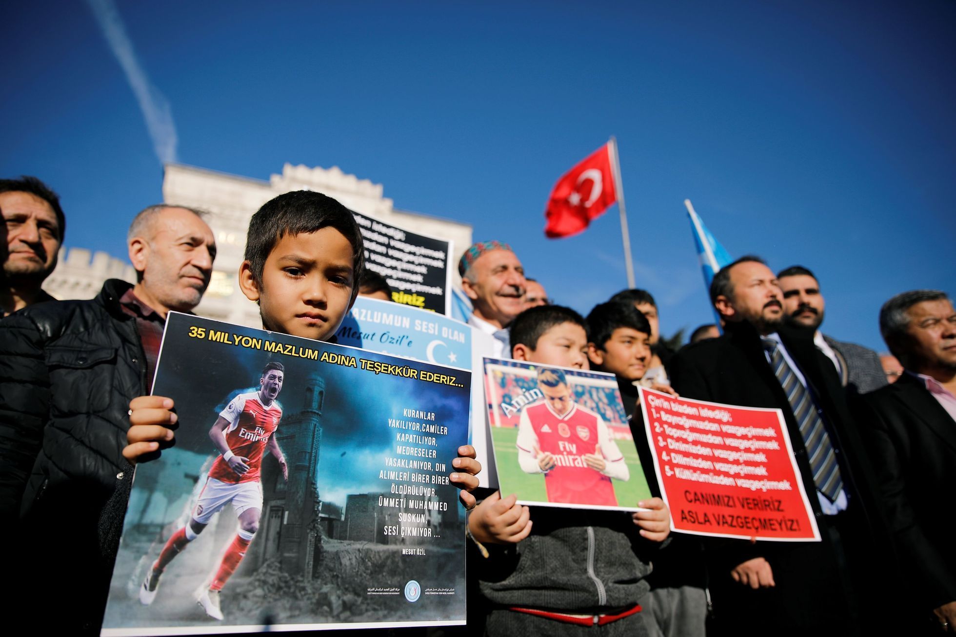 Ujgurský chlapec drží plakát Mesuta Özila během demonstrací před čínskou ambasádou v Istanbulu
