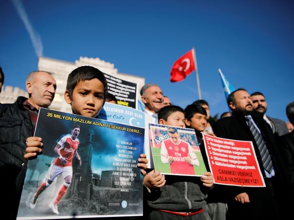 Ujgurský chlapec drží plakát Mesuta Özila během demonstrací před čínskou ambasádou v Istanbulu