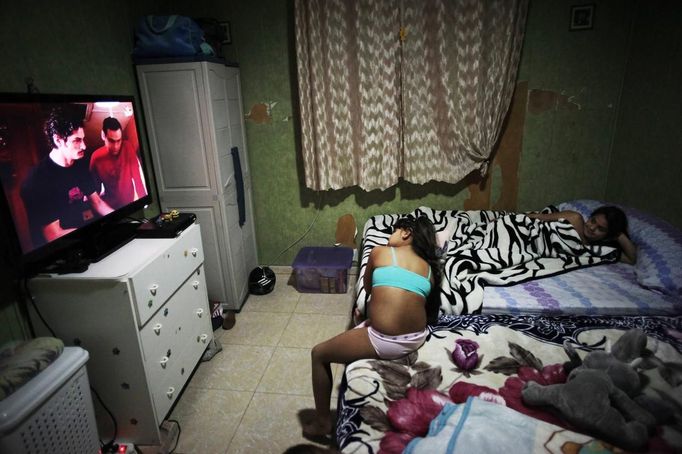 Aroa Gabarri (L) and her sister Gema watch TV in the Spanish gypsy settlement of Puerta de Hierro outside Madrid November 2, 2011. Fifty-four families have been living in Puerta de Hierro, on the banks of the Manzanares river for over 50 years. Since the summer of 2010, the community has been subject to evictions on the grounds that the dwellings are illegal. Families whose houses have been demolished, move in with relatives whose houses still remain while the debris keeps piling up around them as more demolitions take place. Picture taken November 2, 2011. REUTERS/Susana Vera (SPAIN - Tags: SOCIETY) ATTENTION EDITORS - PICTURE 21 OF 31 FOR PACKAGE 'GYPSY SITE DEMOLISHED' SEARCH 'GYPSY SITE' FOR ALL IMAGES Published: Lis. 5, 2012, 4:12 odp.