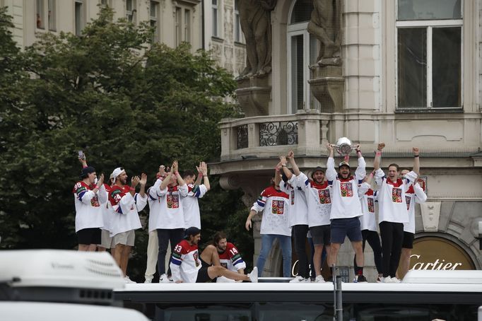 Čeští hokejisté zdraví s trofejí pro mistry světa fanoušky na Staroměstském náměstí ze střechy autobusu