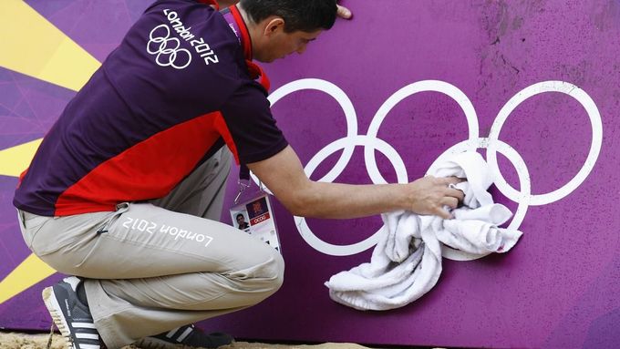 Simon Drew wipes down hoarding surrounding a practice beach volley ball court ahead of teams arriving for the London 2012 Olympic Games in London July 16, 2012. The London 2012 Olympic Games start in 11 days time. REUTERS/Luke MacGregor (BRITAIN - Tags: SPORT VOLLEYBALL OLYMPICS) Published: Čec. 16, 2012, 4:12 odp.