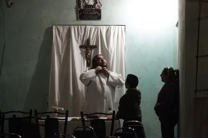 Catholic priest Adolfo Huerta (L), known as "Gofo", gets ready before conducting a mass outside a house in a neighbourhood in Saltillo February 26, 2013. Ordained five years ago, Huerta is an unconventional priest who likes rock music, dyes the ends of his hair red, dresses in black, and enjoys riding his motorcycle. Huerta found God and priesthood while studying philosophy at the Pontifical University in Mexico City and working with HIV-positive patients and sex workers as a social activist. He says it is important to demystify faith and accept people's differences without judgment, and in his sermons he references rock songs, quotes books and tells jokes. Picture taken February 26, 2013. REUTERS/Daniel Becerril (MEXICO - Tags: RELIGION SOCIETY) ATTENTION EDITORS: PICTURE 10 OF 26 FOR PACKAGE 'CHURCH, FAITH AND ROCK'N ROLL' SEARCH 'PRIEST DANIEL' FOR ALL IMAGES Published: Bře. 15, 2013, 10:23 dop.