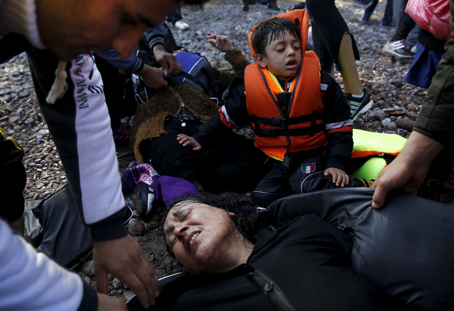 An Afghan migrant woman collapses in exhaustion soon after arriving on an overcrowded raft at a beach on the Greek island of Lesbos