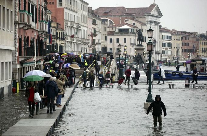 People walk on raised platforms for flood waters during a period of seasonal high water in Venice October 27, 2012. The water level in the canal city rose to 127 cm (50 inches) above the normal level, according to the monitoring institute. REUTERS/Manuel Silvestri (ITALY - Tags: ENVIRONMENT SOCIETY TRAVEL) Published: Říj. 27, 2012, 12:29 odp.