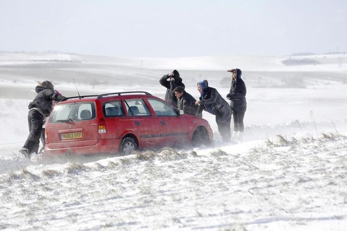 People try to move a car stuck in snow on the South Downs near Brighton in southern England March 12, 2013. Drivers were left stranded on Tuesday following a second day of heavy snowfall in southern England. REUTERS/Luke MacGregor (BRITAIN - Tags: ENVIRONMENT SOCIETY) Published: Bře. 12, 2013, 4:56 odp.