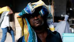 Muž si chrání hlavu ručníkem před horkem v Novém Dillí, Indie, 28. května 2024.