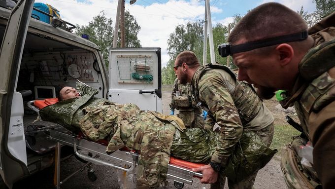 Ukrajinští vojenští zdravotníci ve městě Vovčansk v Charkovské oblasti odnášejí na nosítkách zraněného vojáka, snímek z 12. května 2024.