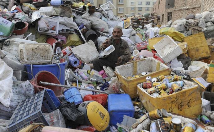 An elderly Uighur man sits on piles of garbage as he picks out the recyclable items at a recycling centre in Aksu