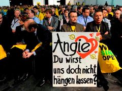 Zaměstnanci centrály Opelu v německém Ruesselsheimu čekají na projev kancléřky Angely Merkelové s tabulí: "Angie, necháš nás na holičkách?"