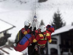 Zraněného rakušana Andrease Budera doprovází dva záchranáři do vrtulníku.