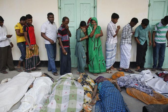 People mourn in front of the remains of their relatives, who died inside the rubble of the collapsed Rana Plaza building, in Savar, 30 km (19 miles) outside Dhaka April 25, 2013. The number of people killed by the collapse of a building in Bangladesh's capital rose to 147 overnight and the death toll could climb further because many people are still trapped inside, Dhaka's district police chief told Reuters on Thursday. REUTERS/Andrew Biraj (BANGLADESH - Tags: DISASTER) Published: Dub. 25, 2013, 3:51 dop.