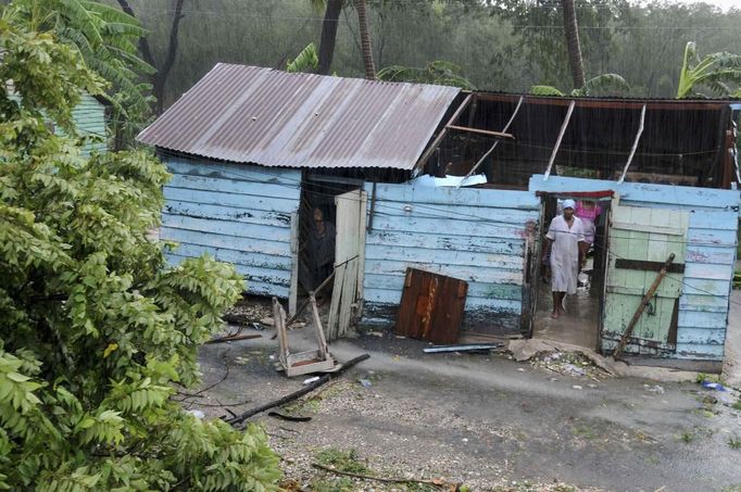 A family stand inside their home, damaged by winds from Tropical Storm Isaac, in El Habanero, Barahona province, August 25, 2012. Tropical Storm Isaac emerged over warm Caribbean waters on Saturday slightly weaker but ready to regroup after dumping torrential rains on the Dominican Republic and Haiti. REUTERS/Ricardo Rojas (DOMINICAN REPUBLIC - Tags: DISASTER ENVIRONMENT) Published: Srp. 25, 2012, 4:41 odp.