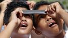 Filipino students share a negative film strip to watch Venus passing between the Sun and the Earth in Silang, Cavite south of Manila June 6, 2012. Venus made a slow transit across the face of the sun on Tuesday, the last such passing that will be visible from Earth for 105 years. REUTERS/Erik De Castro (PHILIPPINES - Tags: SCIENCE TECHNOLOGY SOCIETY) Published: Čer. 6, 2012, 6:04 dop.