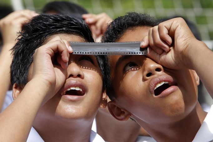 Filipino students share a negative film strip to watch Venus passing between the Sun and the Earth in Silang, Cavite south of Manila June 6, 2012. Venus made a slow transit across the face of the sun on Tuesday, the last such passing that will be visible from Earth for 105 years. REUTERS/Erik De Castro (PHILIPPINES - Tags: SCIENCE TECHNOLOGY SOCIETY) Published: Čer. 6, 2012, 6:04 dop.