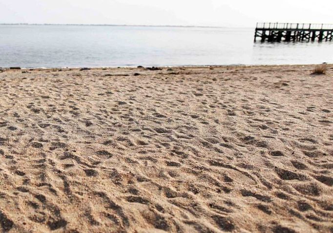 Záběr z pláže Oak Beach. Vyšetřovatelé už odjeli, v písku zůstaly pouze četné stopy.