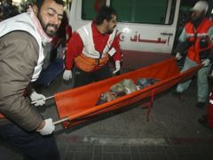 Palestinští zdravotníci přenášejí do sanitky chlapce, zraněného přoi izraelském útoku.
