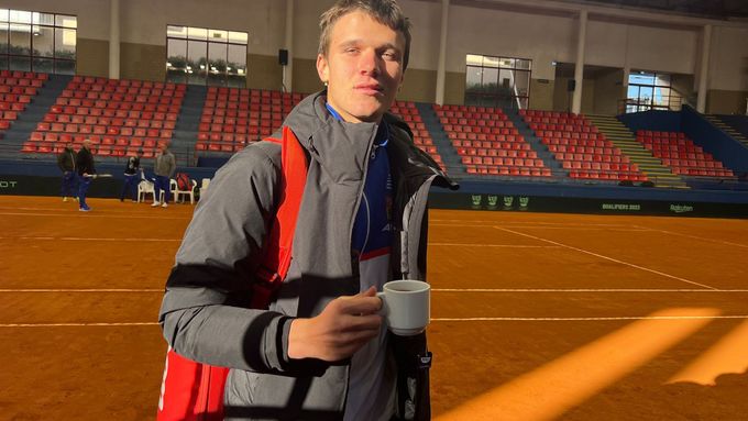 Jakub Menšík v bundě a s teplým čajem v ruce při tréninku českých tenistů v promrzlé hale v Portugalsku před zápasem Davis Cupu