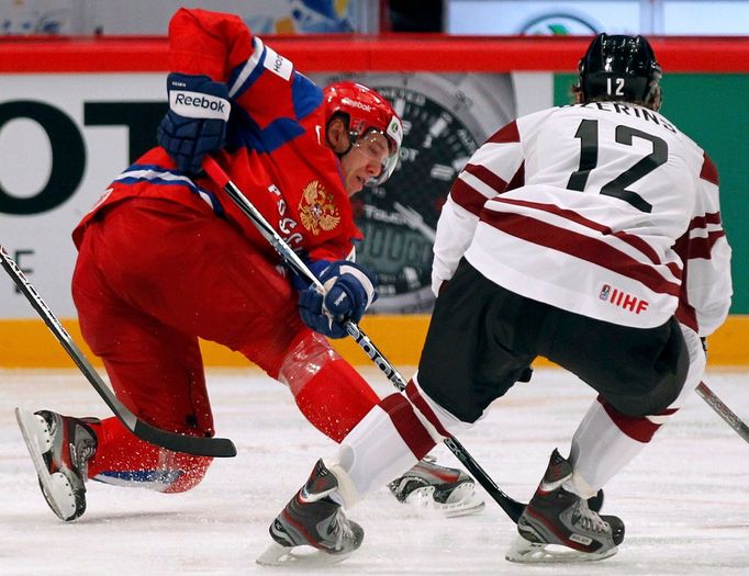 Nikolaj Kuljomin a Andris Dzerins bojují o puk v utkání MS v hokeji 2012 Rusko - Lotyšsko.