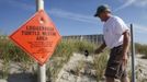 South Carolina United Turtle Enthusiasts (SCUTE), head coordinator Jeff McClary uses signs and fencing to mark a Loggerhead turtle nest on Litchfield Beach, South Carolina August 9, 2012. Turtle volunteers walk the area's beaches along South Carolina's coast daily during the nesting season, looking for signs of turtle activity and keeping tabs on the progress of the endangered species of turtles that lay their eggs along the coast. Photo taken August 9, 2012. REUTERS/Randall Hill (UNITED STATES - Tags: ANIMALS ENVIRONMENT) Published: Srp. 21, 2012, 12:52 odp.